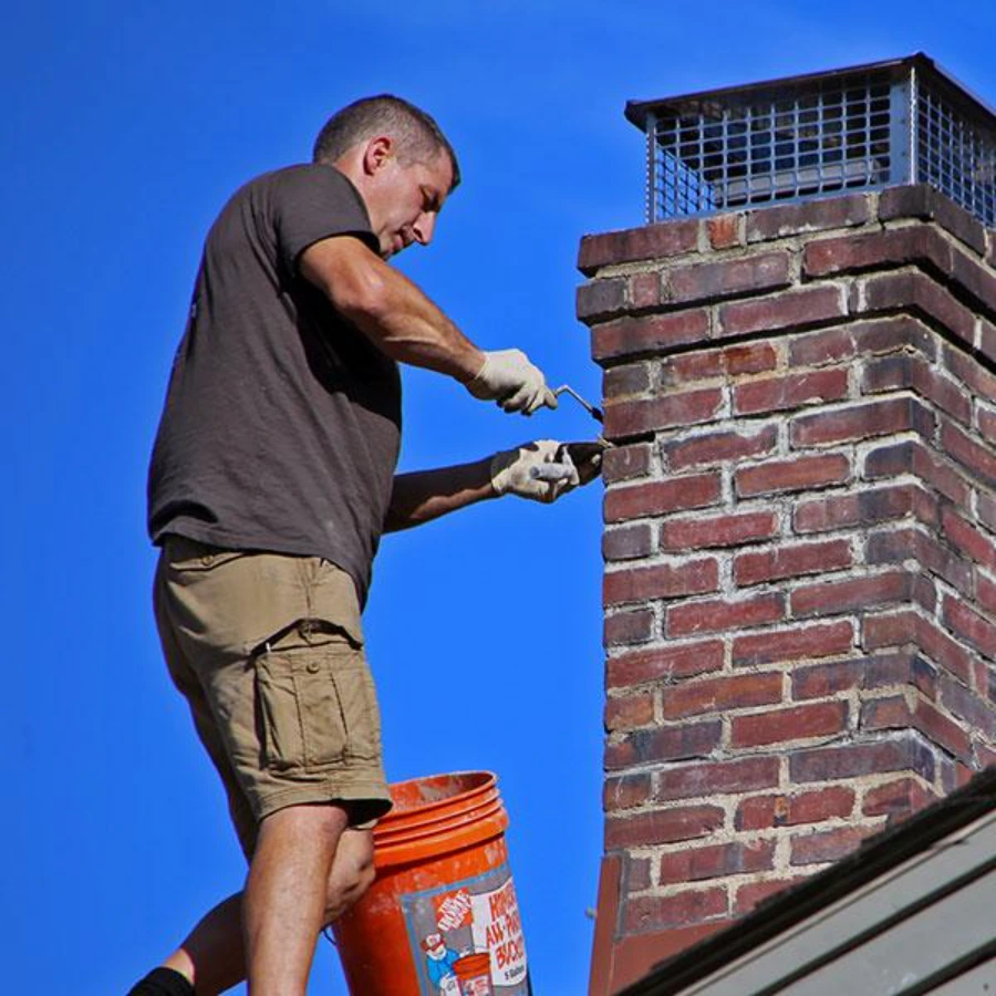 Mason repairing a cracked chimney crown and flashing